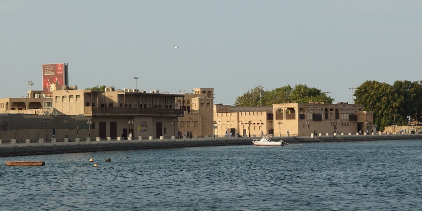 Traditional houses with a round watchtower on a rocky hill under a partly cloudy sky, one of the top historical places in Dubai.