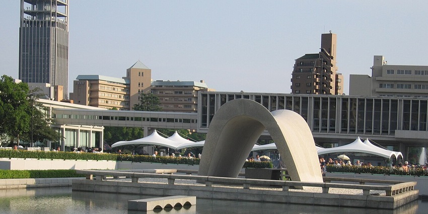 Curved stone monument over a reflecting pool, with modern buildings in the background, is one of the top historical places in Japan.