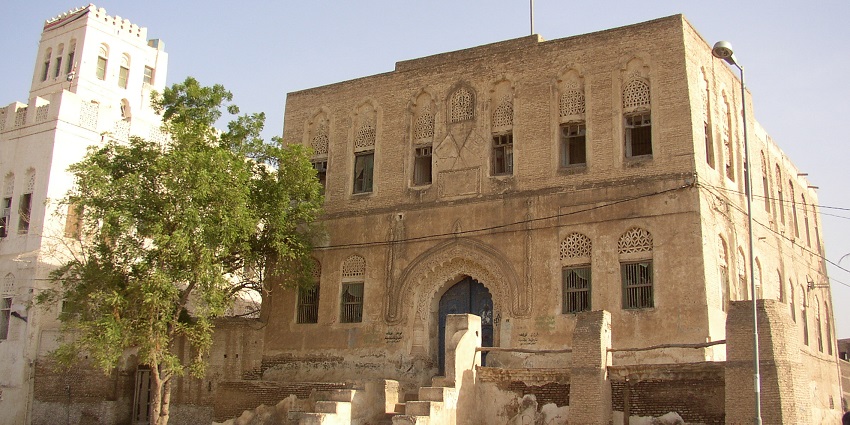 Narrow street lined with aged buildings featuring arched doorways, one of the top historical places in Yemen.