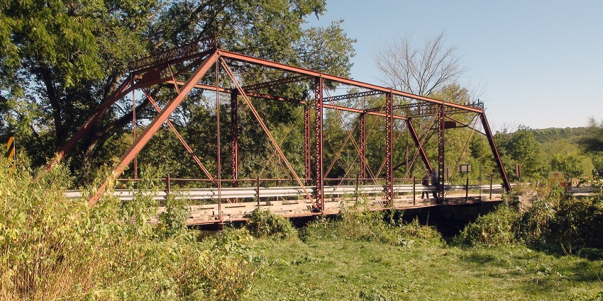 Historic Forestville with an old iron bridge, railings on the bridge and surrounded by greenery