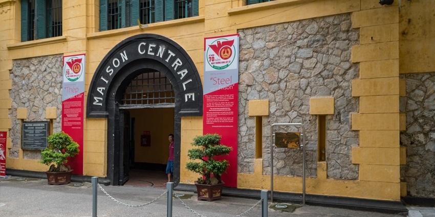 Outside view of Hoa Lo Prison with displays and iron gates.