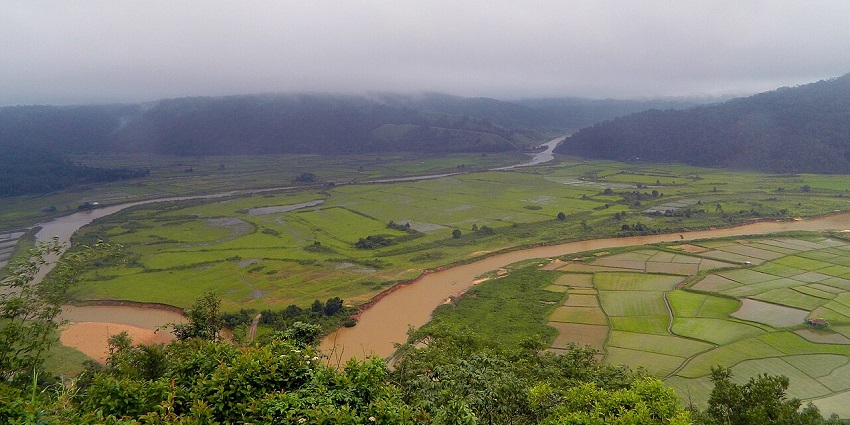 Lalong Park in Jaintia Hills with green plains, a brown water body of the river and hills.