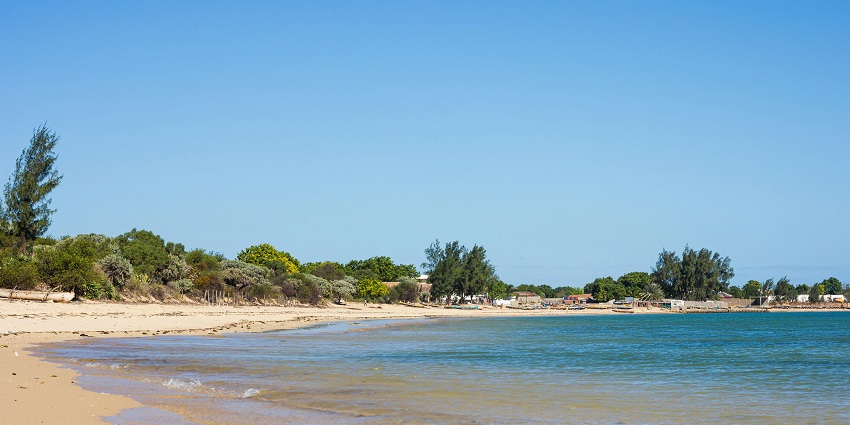 A tropical beach on Île Sainte-Marie in Madagascar with crystal clear water, fishing boats, palm trees, and a peaceful coastal view.