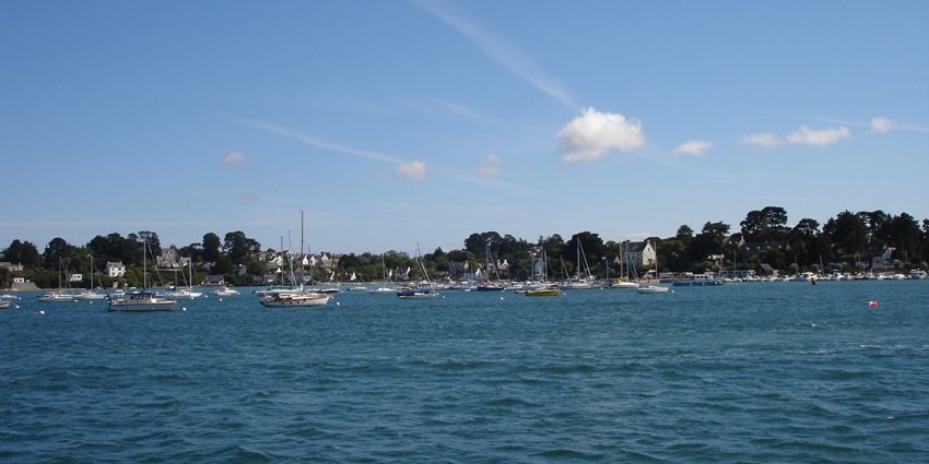 Harbor of Île-aux-Moines in Morbihan, France, with boats docked under a clear blue sky