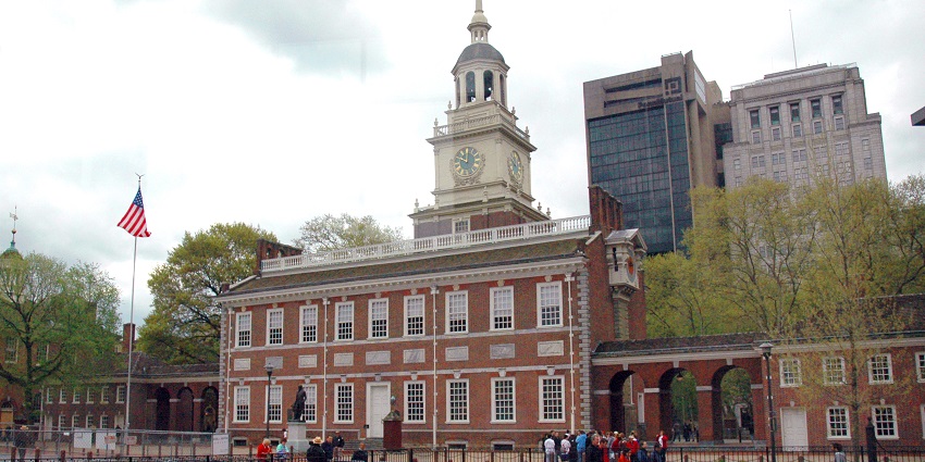 Historic brick building with clock tower, blooming tulips, and people gathered outside.