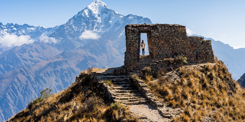 The stone archway of Intipunku, the Sun Gate, is positioned at a mountain trail entrance.