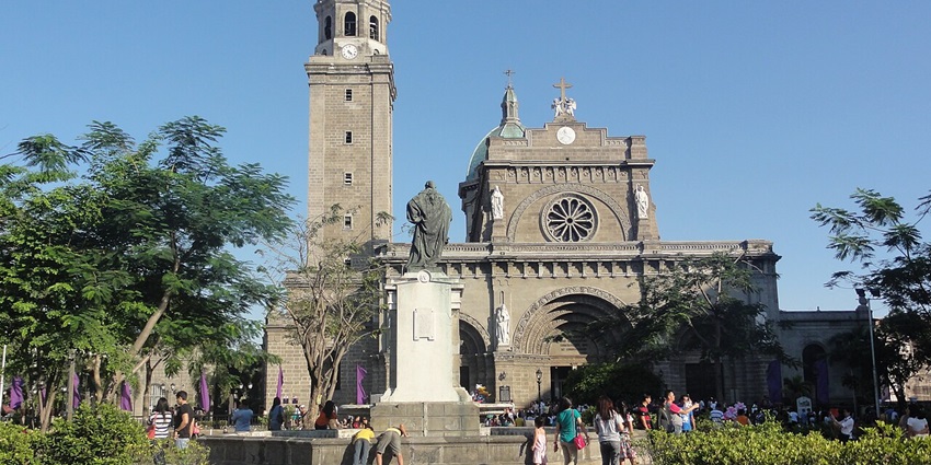 Entrance to the Intramuros with a welcome signboard, vehicles and a policeman standing