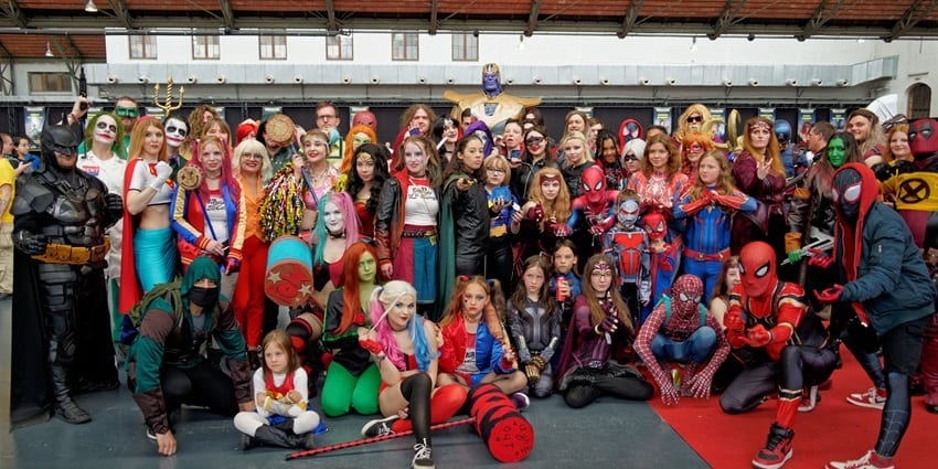 An image of cosplayers dressed as Marvel and DC superheroes at a fantastic comic event.
