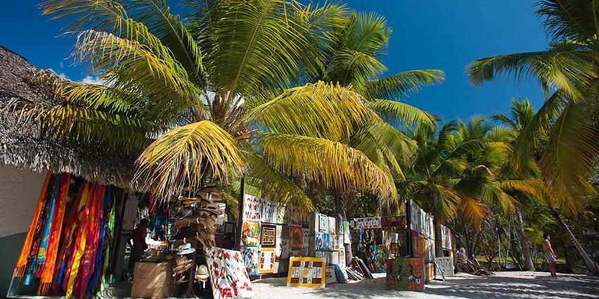 Vibrant beachside market with colorful textiles, paintings, and souvenirs