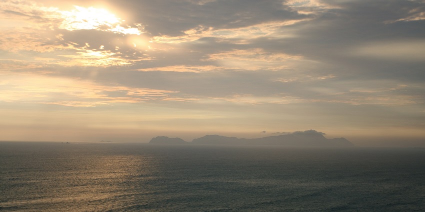 Distant view of arid San Lorenzo Island with rugged terrain and calm waters, among the best islands in Peru.