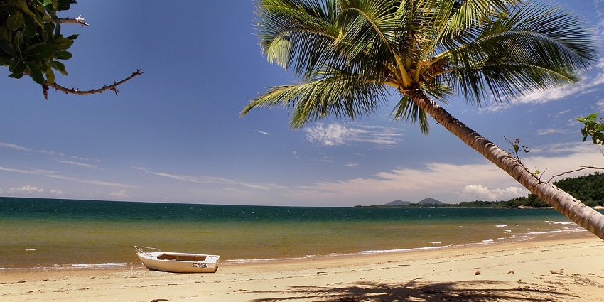 View of Dunk Island beach with turquoise waters and a lush green hill in Far North Queensland.
