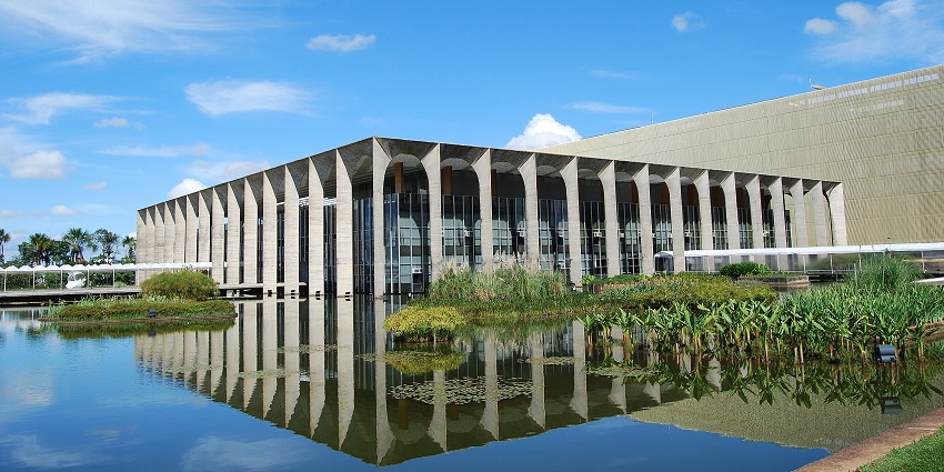 The modernist building of Itamaraty Palace, surrounded by a reflective pond and greenery.