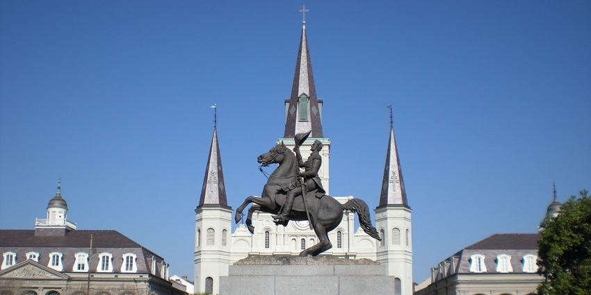 Bustling Jackson Square with street artists and St. Louis Cathedral backdrop.