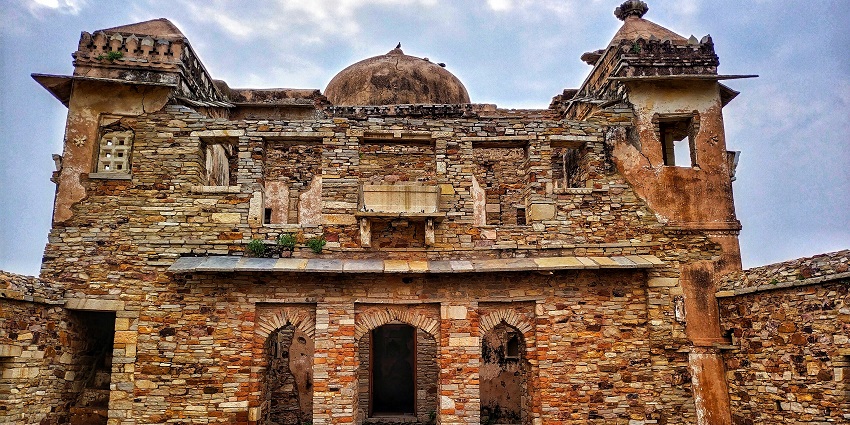 Jaigad Fort with stone walls overlooking the sea and surrounded by greenery and open skies.
