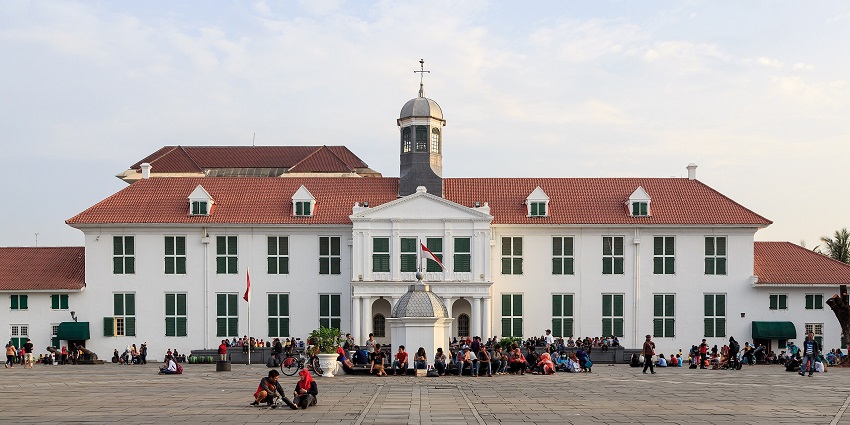 Colonial-era museum building with red-tiled roof and visitors walking in the courtyard.