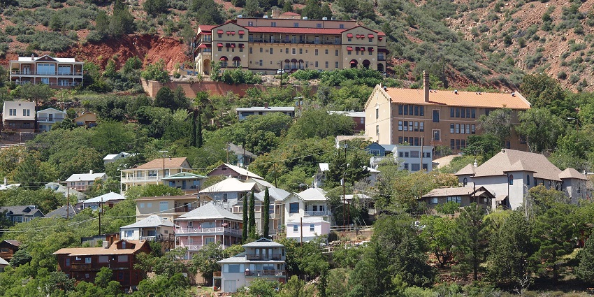 Hillside town with colourful houses and historic buildings surrounded by lush vegetation.