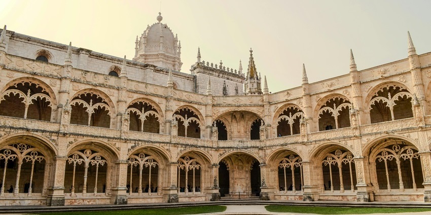 The elaborate facade of Jerónimos Monastery in Lisbon under a blue sky.