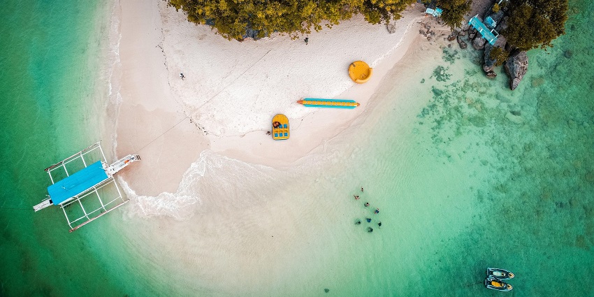 Aerial view of Juan de Nova Island showing sandy beaches, green vegetation, and surrounding ocean waters.