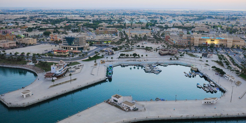 Aerial view of a waterfront cityscape featuring a marina with boats docked, surrounding piers,