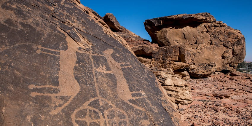Jubbah rock carvings with old carvings on the stones and big rocks under the blue sky
