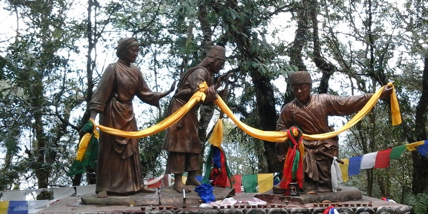Statue at Kabi Longstok representing the historic friendship pact amid lush greenery