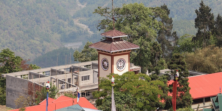The clock tower in Kalimpong stands tall in the town centre, surrounded by buildings.