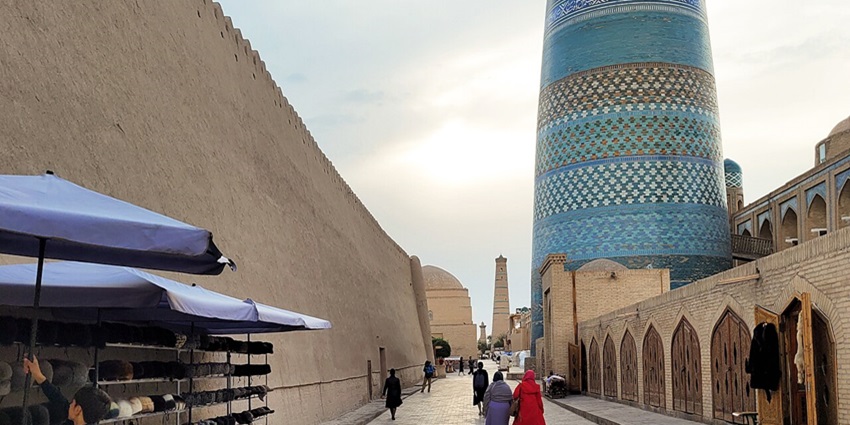 Kalta Minor with a wide greenish minaret, tall minaret in the back and people on the street