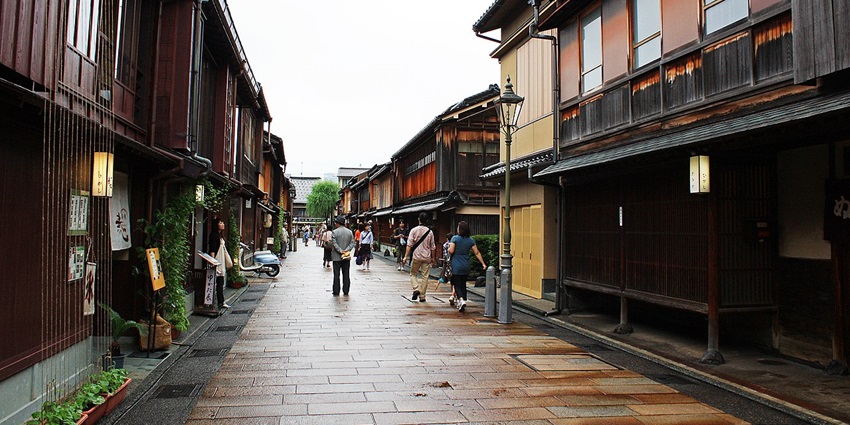 Street of Kanazawa's geisha district with people walking, small houses and street lamps