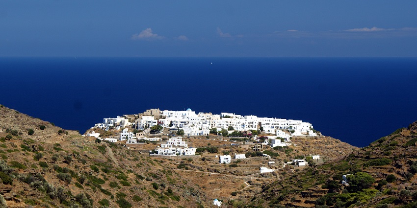 Kastro village with distant white architectural buildings, small hills and blue sea.
