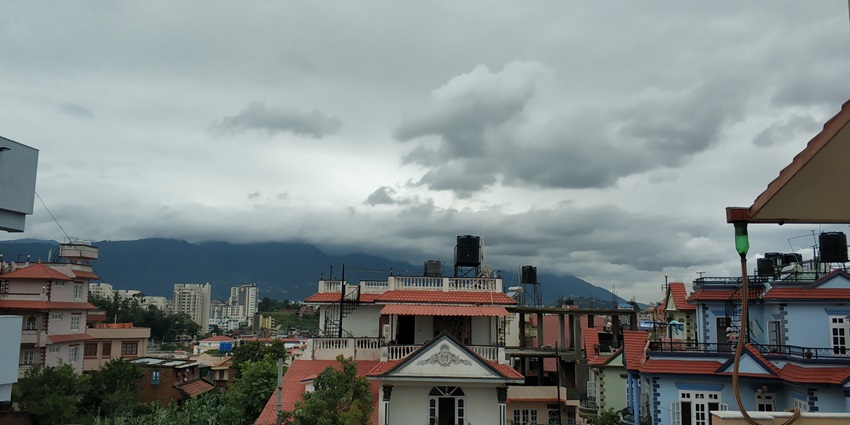 Kathmandu Valley, with many houses in front and mountains in the back under a cloudy sky