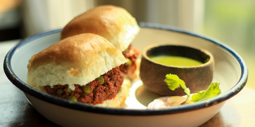 Minced spiced meat curry served with soft pav buns, garnished with coriander and onions.
