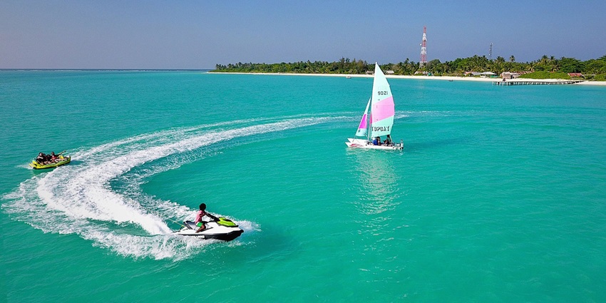 Kelaa Island at a distance, with water sports activities going on and distant greenery