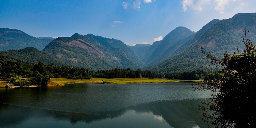 Scenic Kerala landscape with palm trees, hills, and serene water bodies