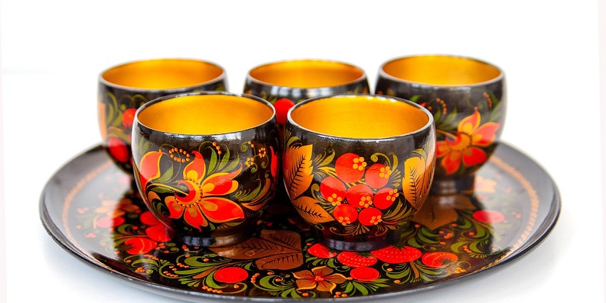 Brightly decorated Russian Khokhloma tableware in red, gold, and black.