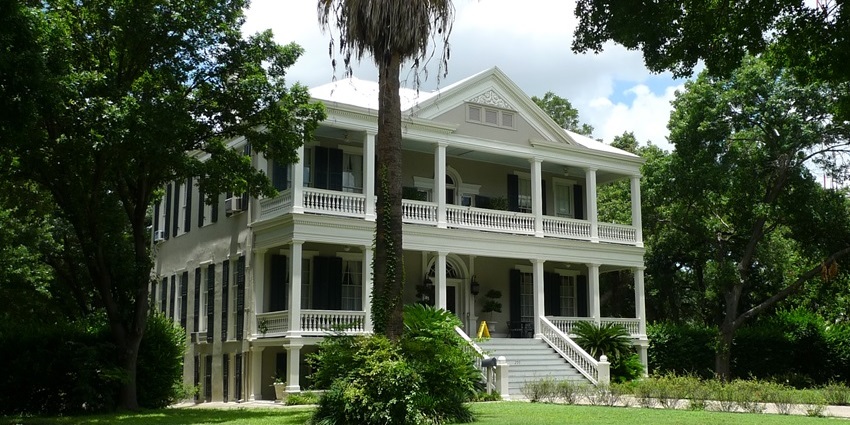 Big mansion in King William's historic district with white architecture, stairs, and greenery