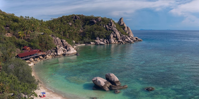 Ko Tao with huge stone structures, and a hut among the green mountains.