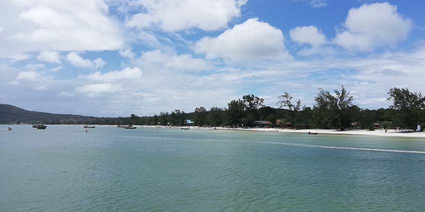 A scenic view of lush green hills meeting turquoise waters on one of the picturesque islands in Cambodia.