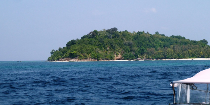View of a lush green tropical island surrounded by clear blue waters, part of the scenic islands in Cambodia.