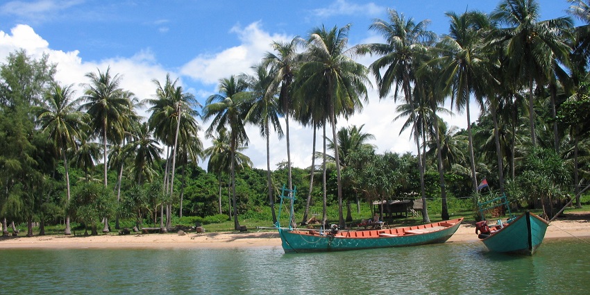 A tranquil view of Koh Thmei, one of the peaceful islands in Cambodia, featuring lush greenery, sandy shores, and surrounding clear blue waters.