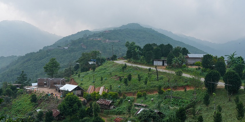 Village in Meghalaya with traditional houses, electricity poles and lush greenery.