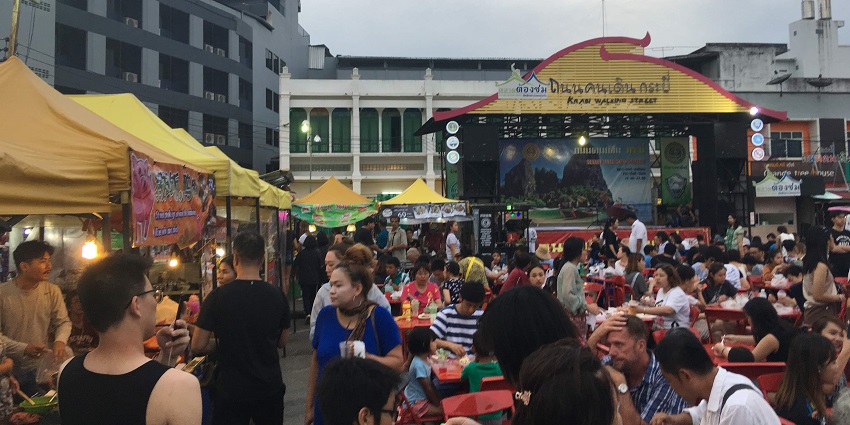 Bustling weekend market with food stalls, handmade goods, music, and street performances