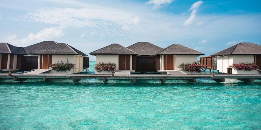 Small cabins lined on the bright blue waters of Kudadoo Private Island in the Maldives