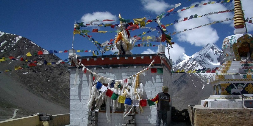 Colourful paper strings at the temple with snowy mountain peaks in the background.