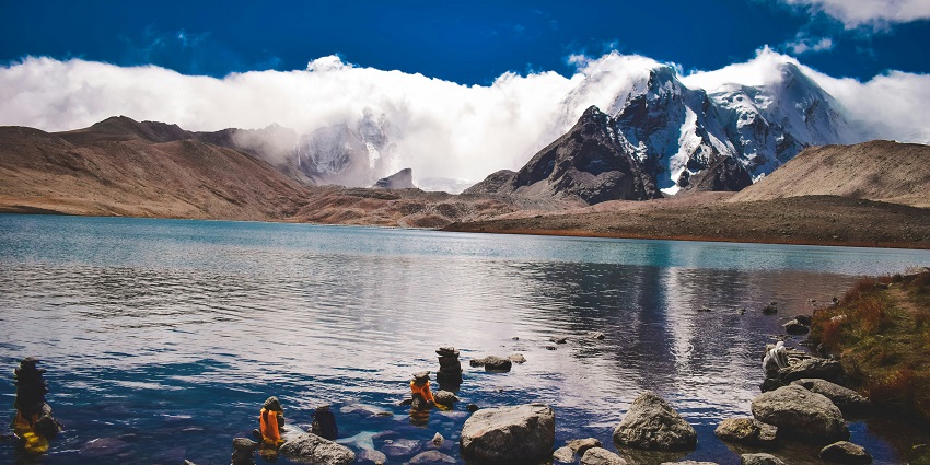High-altitude lake surrounded by snow-covered mountains and clear blue skies in Sikkim