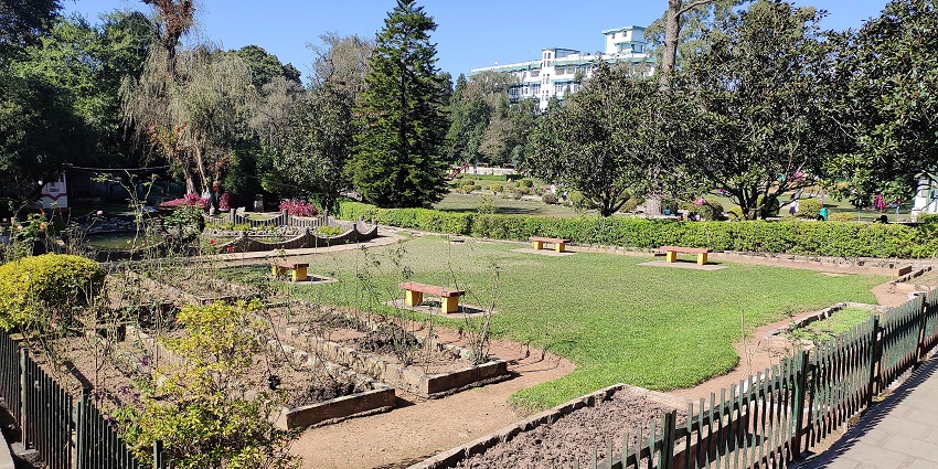 Lady Hydari Park in Shillong City with multiple benches, plants, green trees and plains.