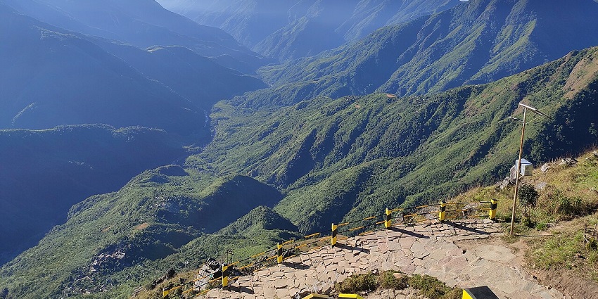 Laitlum Canyon from a distance with yellow, black railings, stone trails and mountains.
