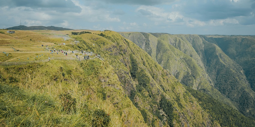 Laitlum Canyon in Meghalaya with broken structures, yellow railings and green mountains.