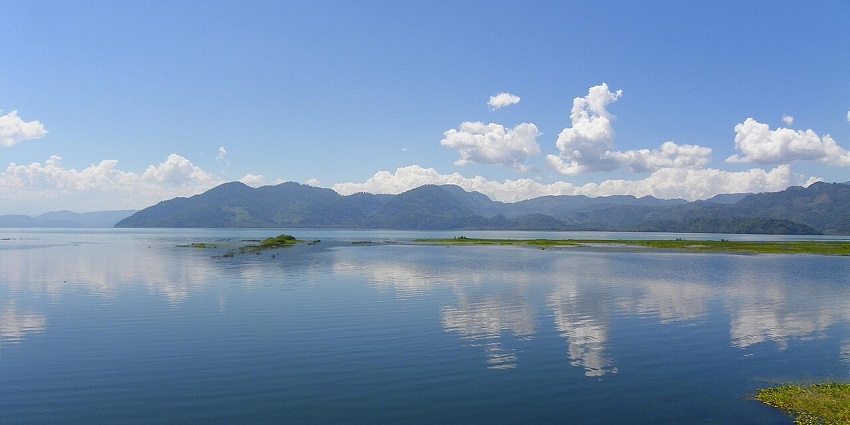 Serene lake surrounded by mountains reflects the blue sky, one of the most beautiful places to visit in Honduras