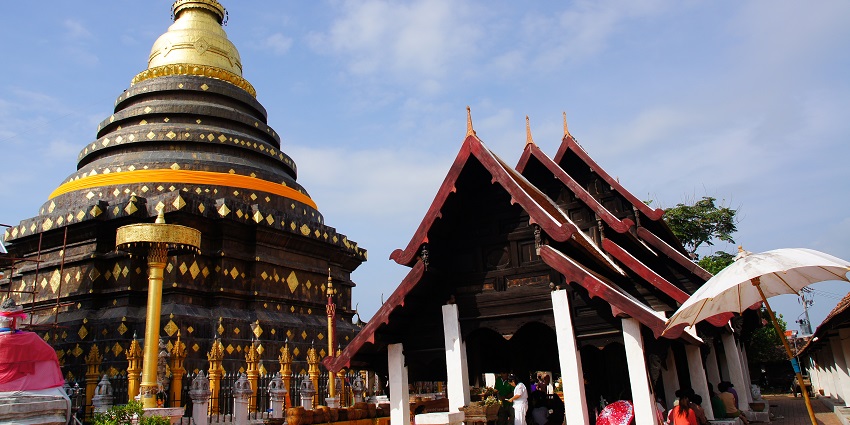 Lampang Luang with its unique architecture, detailed pillars, and people visiting the temple.