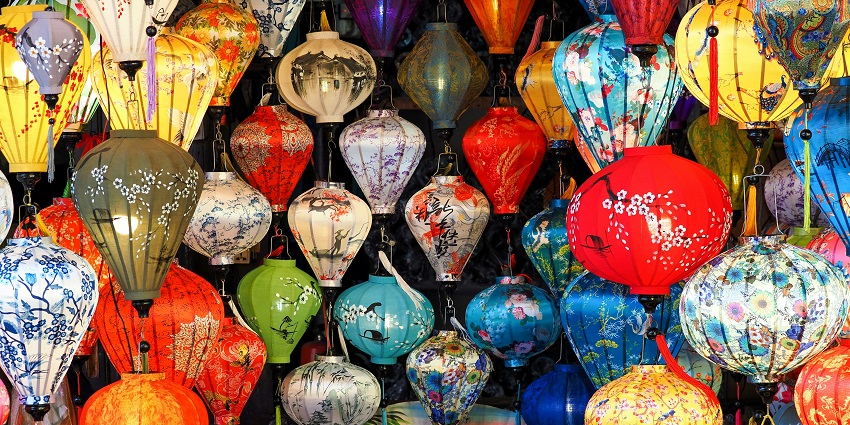 A bunch of colourful lanterns hanging from the ceiling in a festive indoor display.